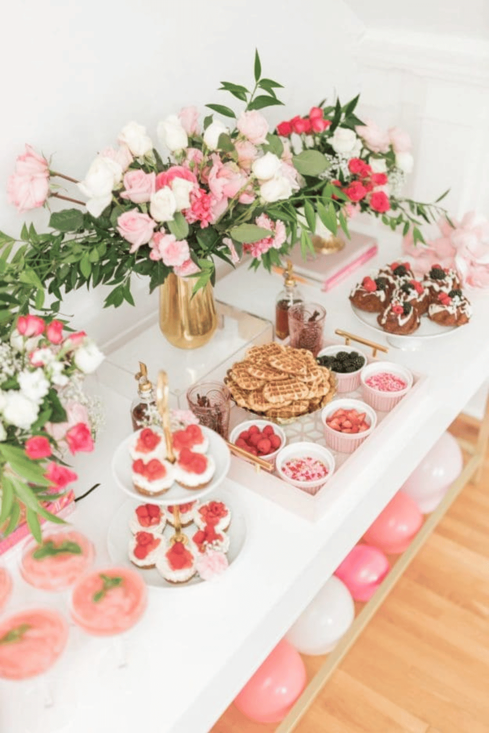 Galentine’s brunch table with waffles, flowers, and pink desserts