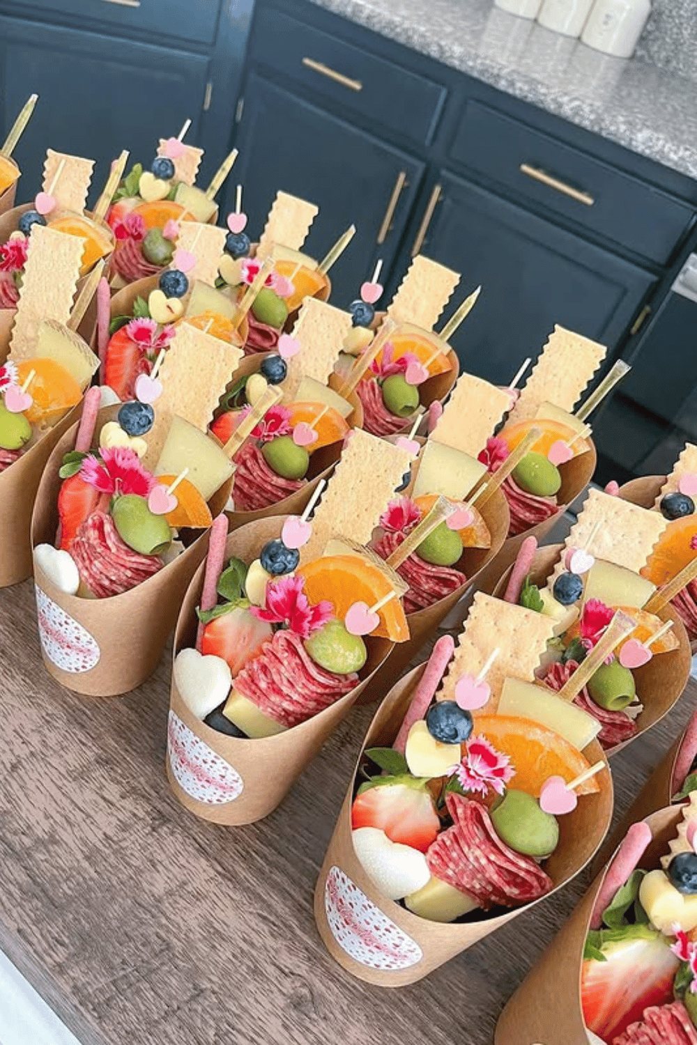 Individual snack cones with fruit, cheese, and meats for galentine’s party