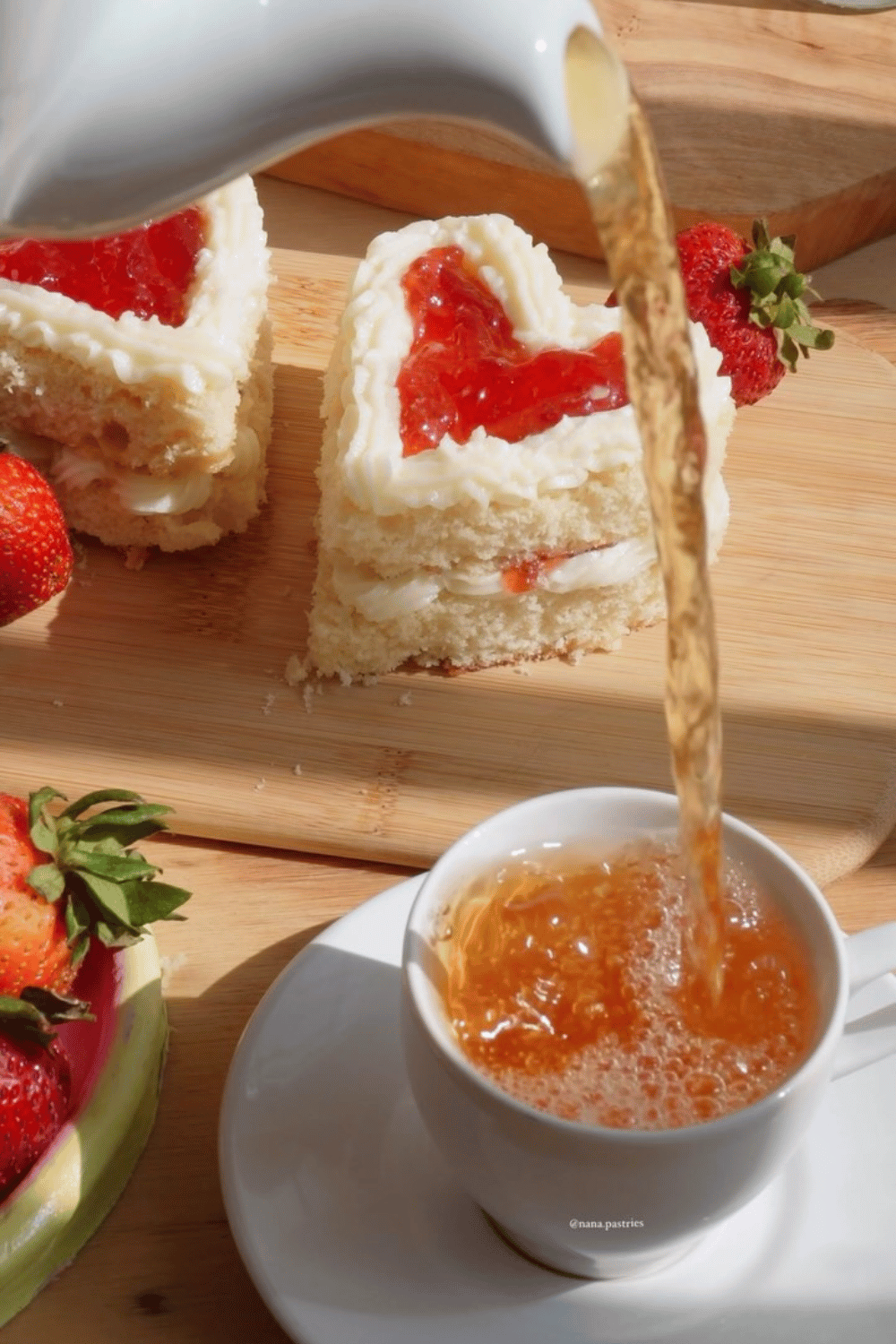 Tea being poured next to heart-shaped cake slices for galentine’s day drinks table