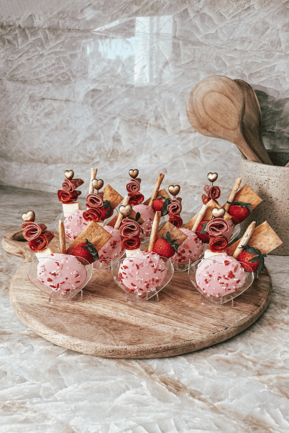 Individual galentine’s charcuterie cups with cheese, fruit, and heart picks