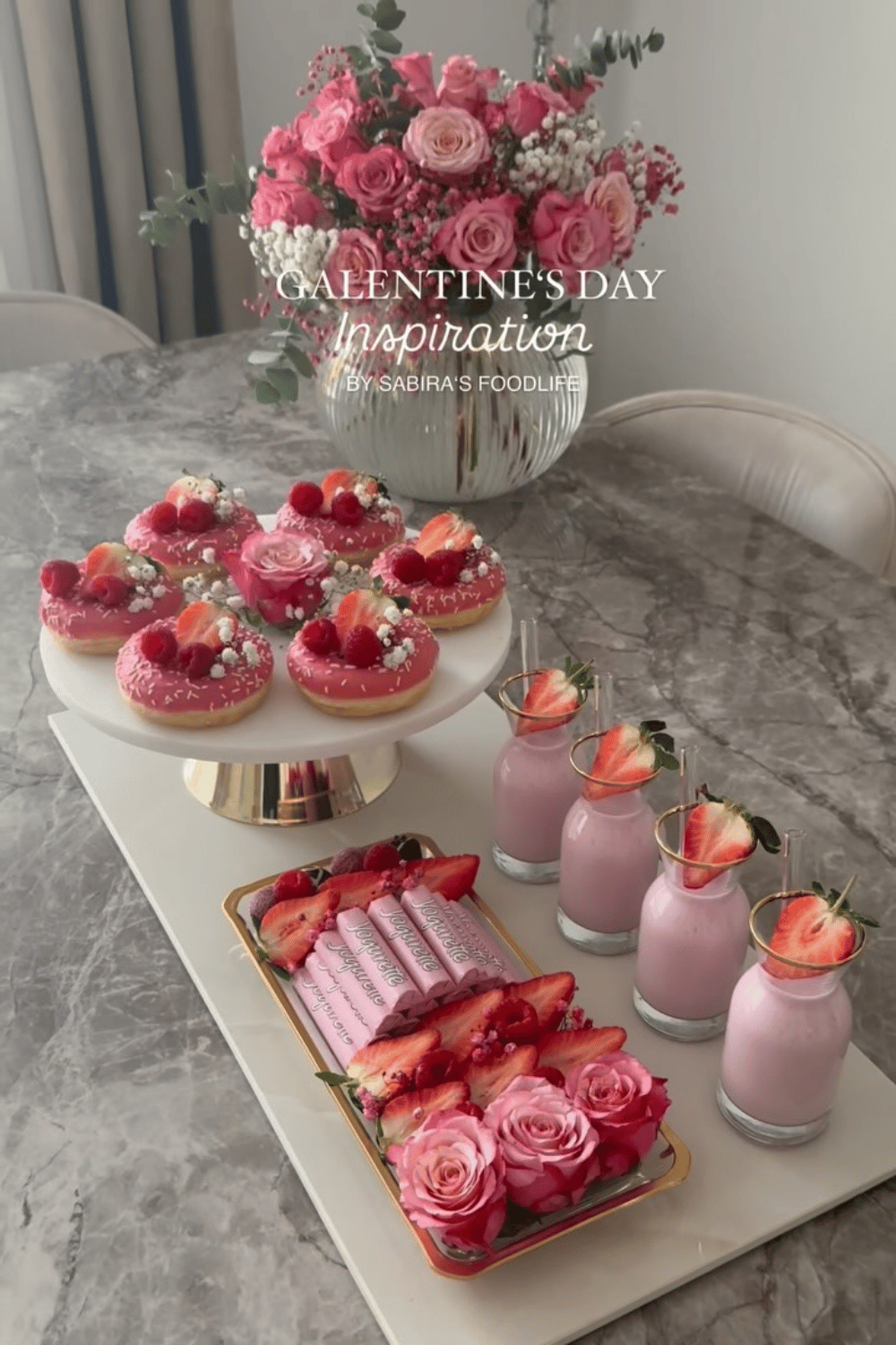 Pink galentine’s day dessert table with donuts, strawberries, and pink milk drinks