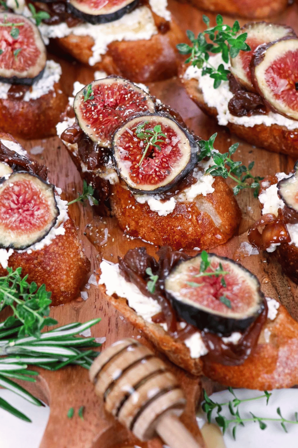Fig and ricotta crostini topped with caramelised onions, fresh figs, herbs, and a drizzle of honey on a wooden board, perfect for Galentine’s party food ideas.
