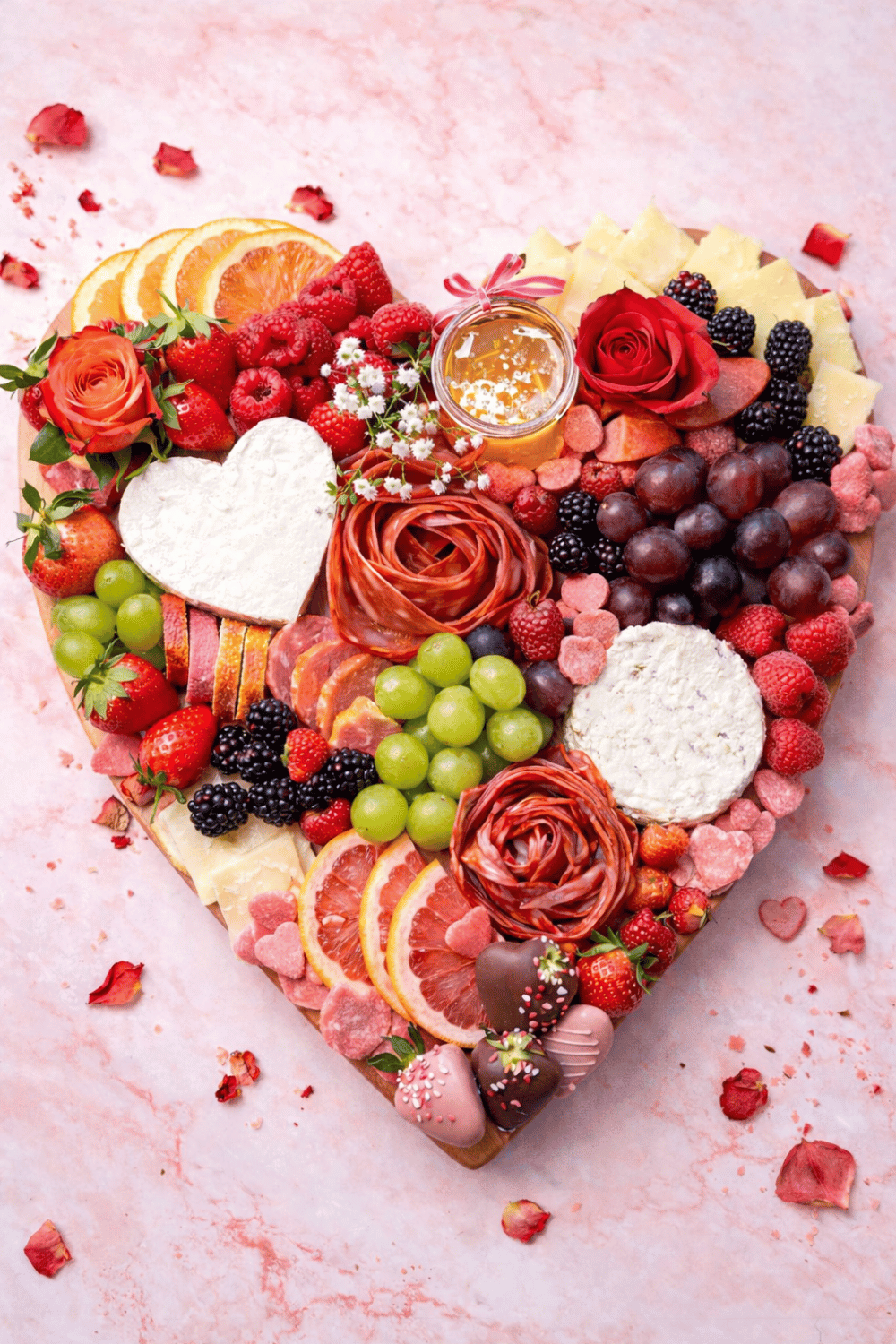 Heart-shaped galentine’s charcuterie board with fruit, cheese, and chocolates
