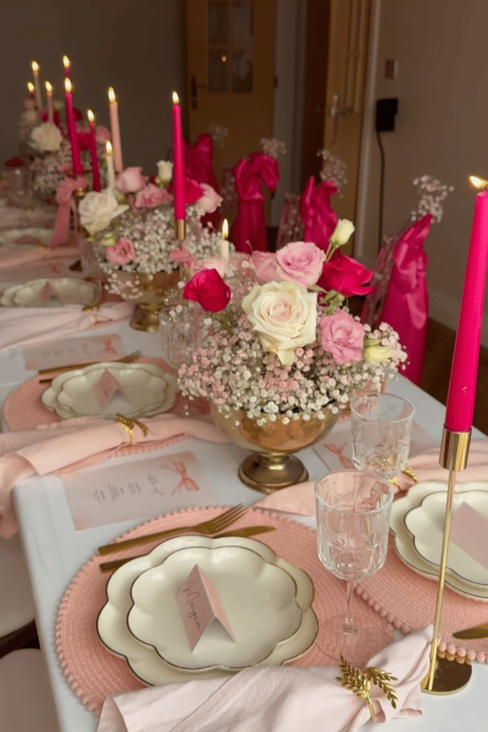 Elegant galentine’s dinner table with pink plates, flowers, and tall candles