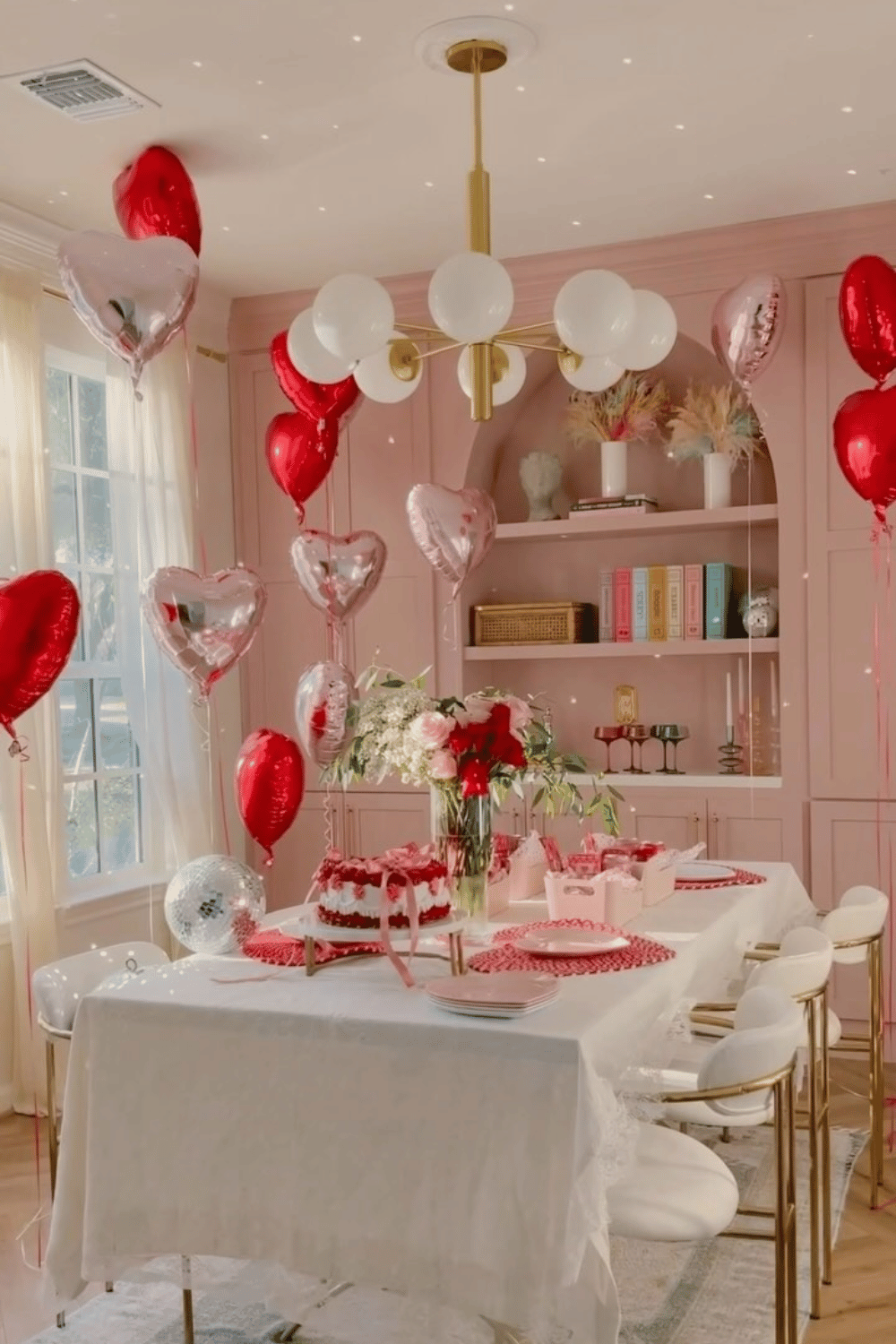 Pink galentine’s dining room table with balloons and themed decor