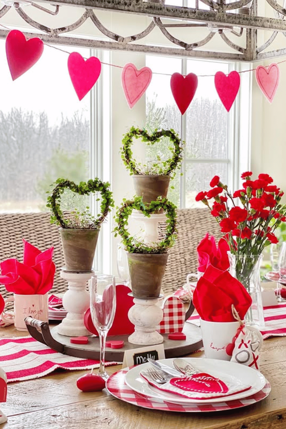 Natural Galentine’s tablescape with wooden heart decor, greenery, and red accents