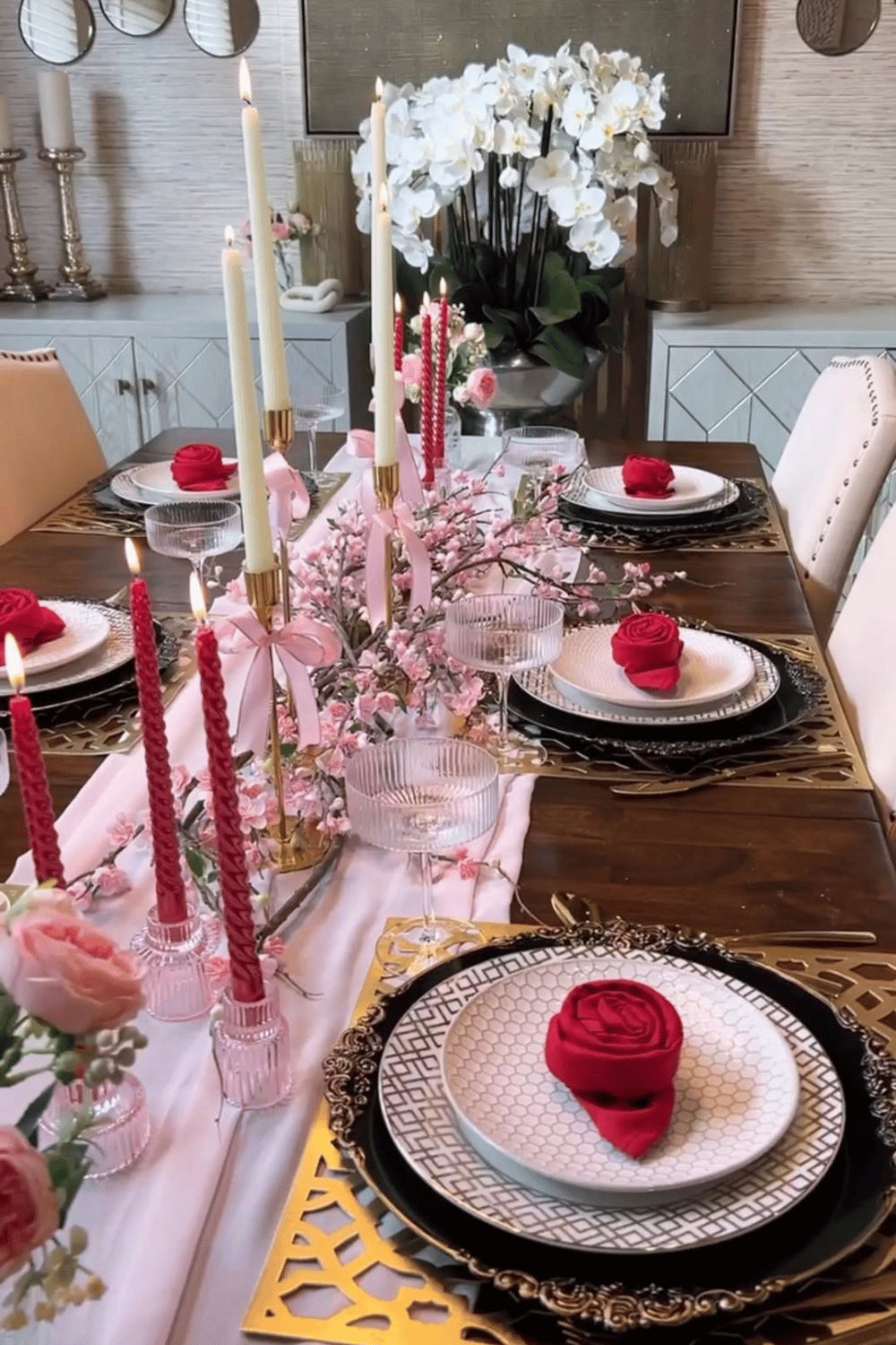 Elegant Galentine’s dinner table with tall candles, pink florals, and layered place settings
