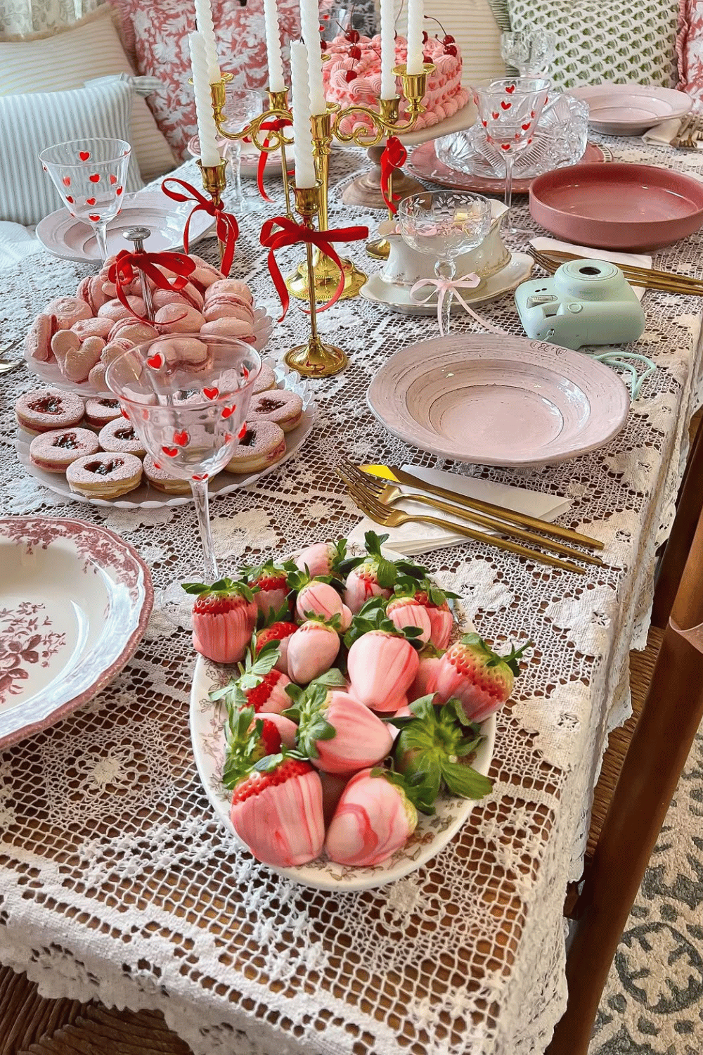 Galentine’s dessert table with strawberries, pastries, candles, and lace tablecloth
